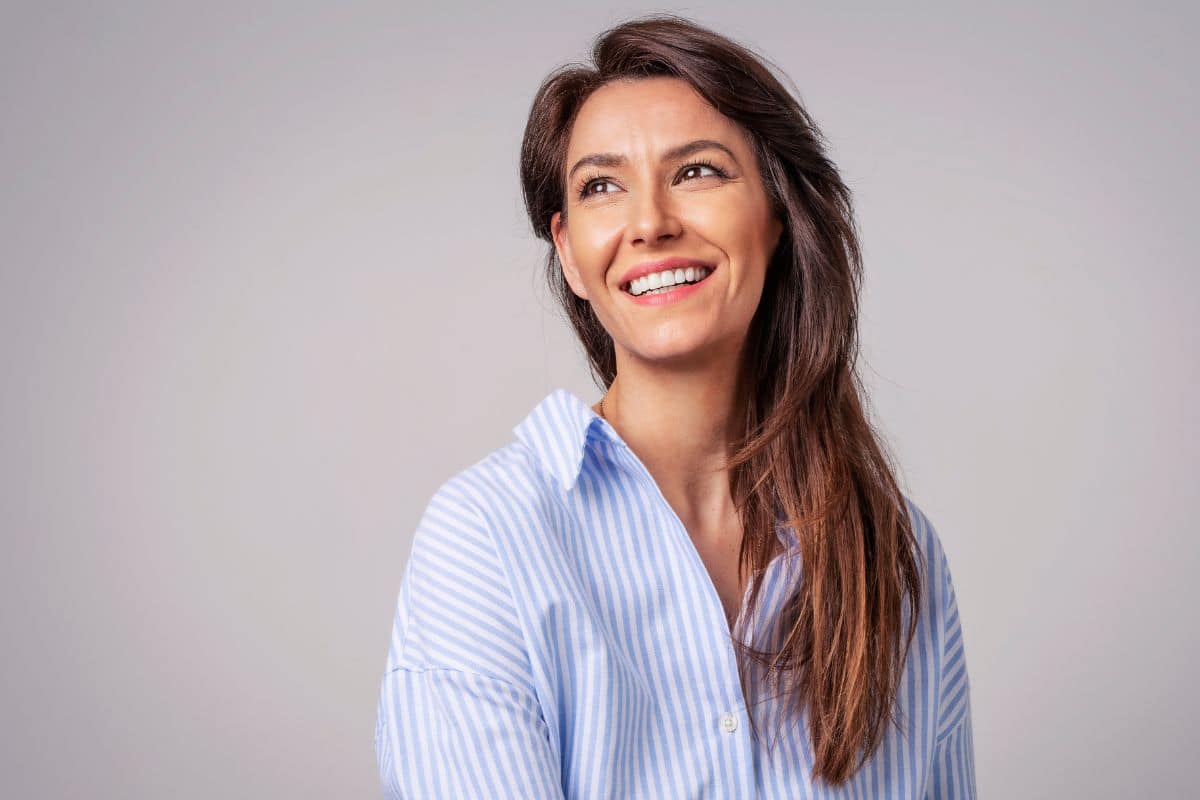 Smiling woman laughing in a studio setting, representing confidence after receiving a dental crown at magnolia family dentistry