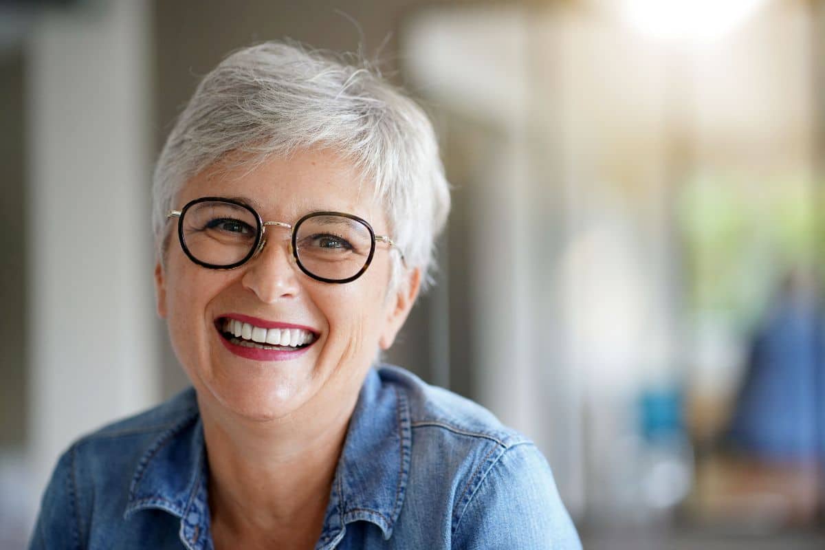 Smiling older woman wearing glasses with a natural-looking, healthy smile indoors