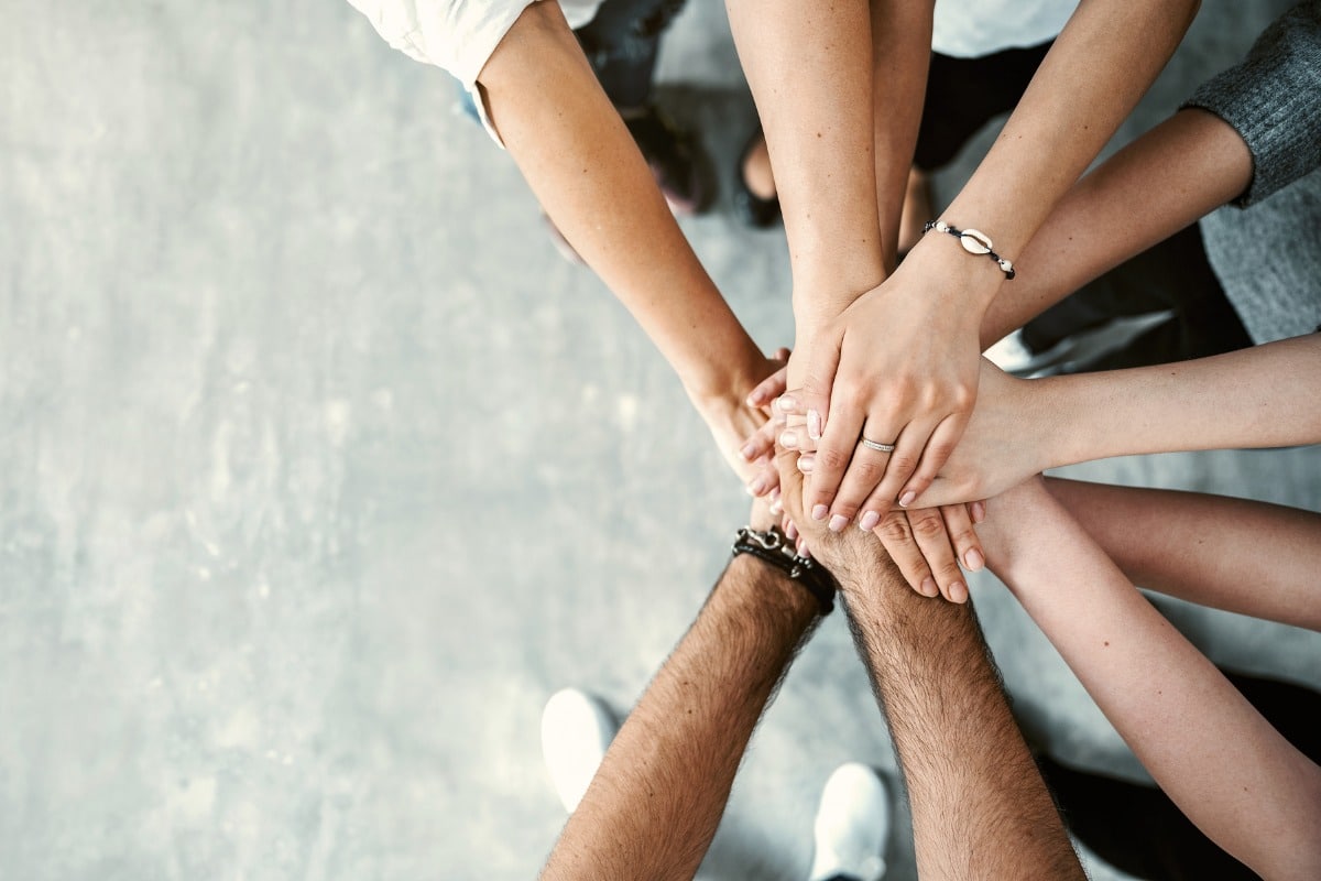 Group of people stacking their hands together in a teamwork gesture.