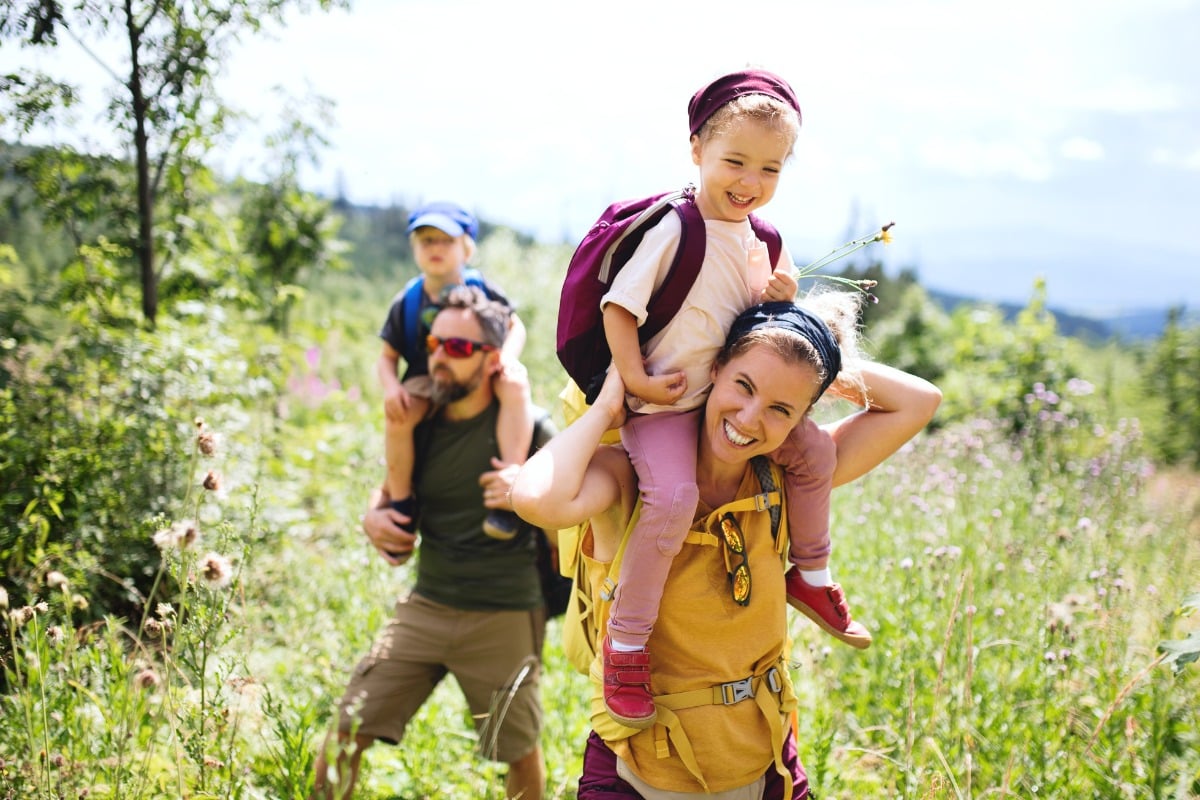 Smiling family hiking outdoors together, representing healthy, active lifestyles supported by family dental care.