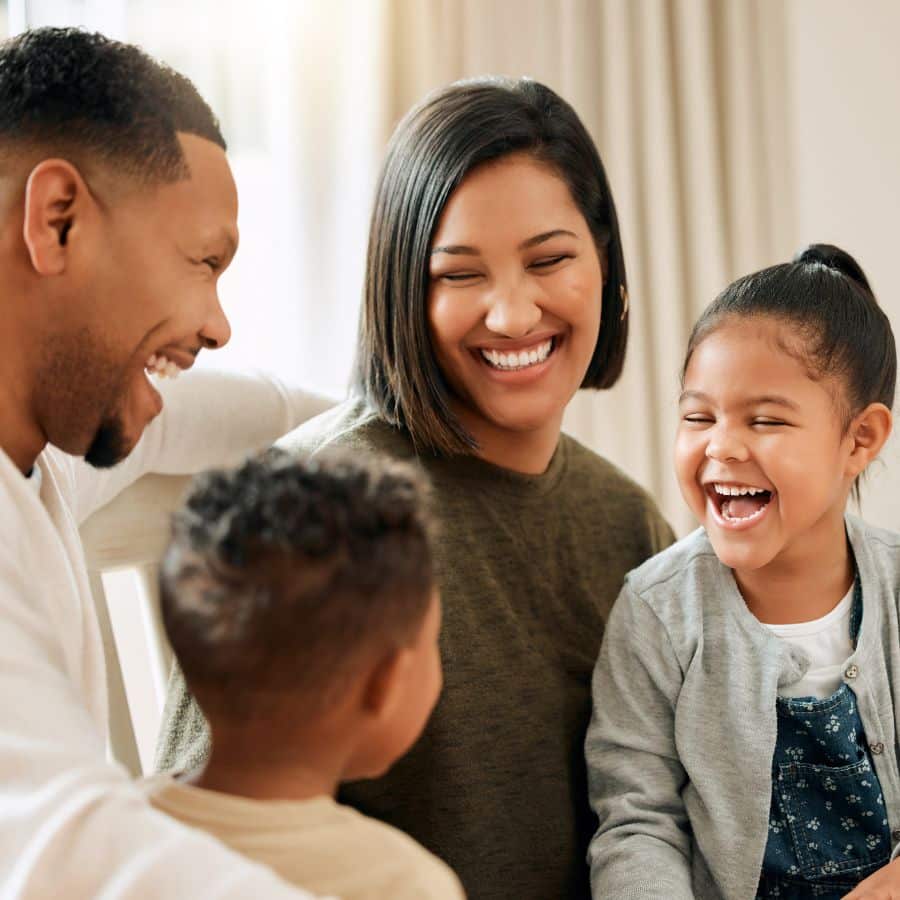 Smiling family of four laughing together indoors.