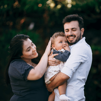 Young parents holding their baby while smiling, representing how Cherry dental financing work