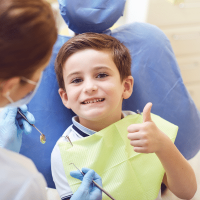 Little boy sitting in a dental chair giving thumbs up, representing best dentist for children
