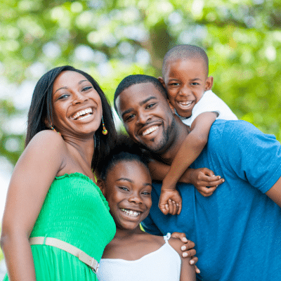 Family of four hugging and smiling, representing benefits of a family dentist for all ages