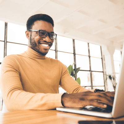Man smiling while working on a laptop, representing new website