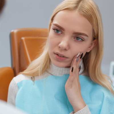 Woman holding her jaw in pain at the dentist, representing what to do in a dental emergency