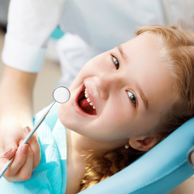 Little girl with head turned toward camera, smiling, representing what to expect at your childs first dental visit